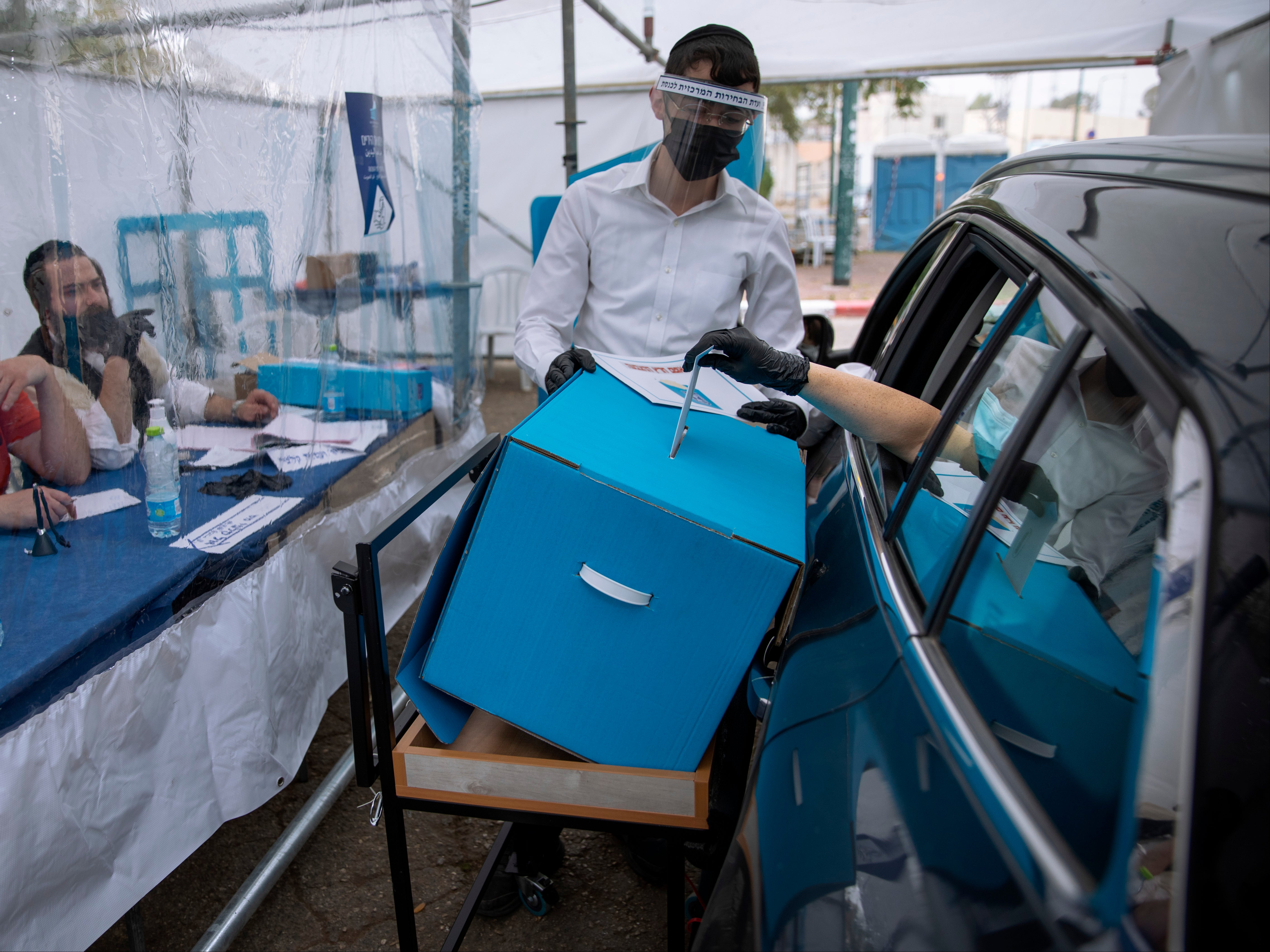 A women votes for Israel’s parliamentary election at a special drive-in polling station for people who are in quarantine for coronavirus in Ramat Gan