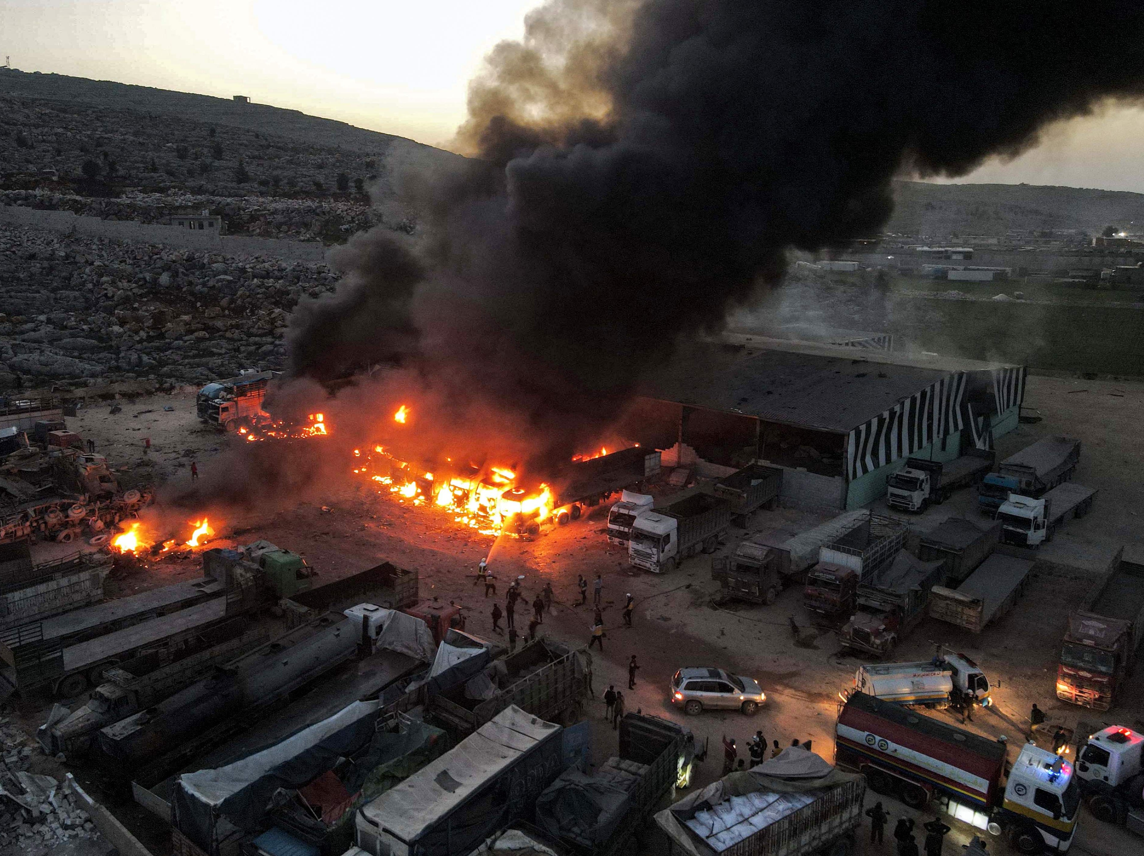 An aerial view of billowing smoke coming from burning trucks and freight vehicles