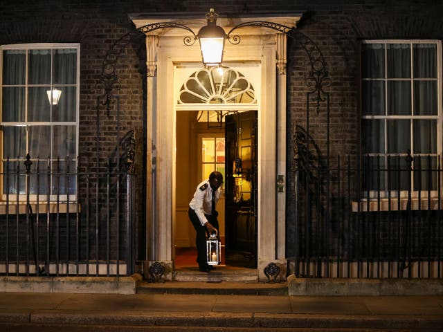 A doorman places a candle on the doorstep of Downing Street, as part of a day of reflection to mark the anniversary of Britain's first coronavirus disease (COVID-19) lockdown