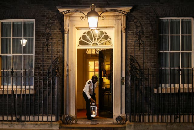 A doorman places a candle on the doorstep of Downing Street, as part of a day of reflection to mark the anniversary of Britain's first coronavirus disease (COVID-19) lockdown