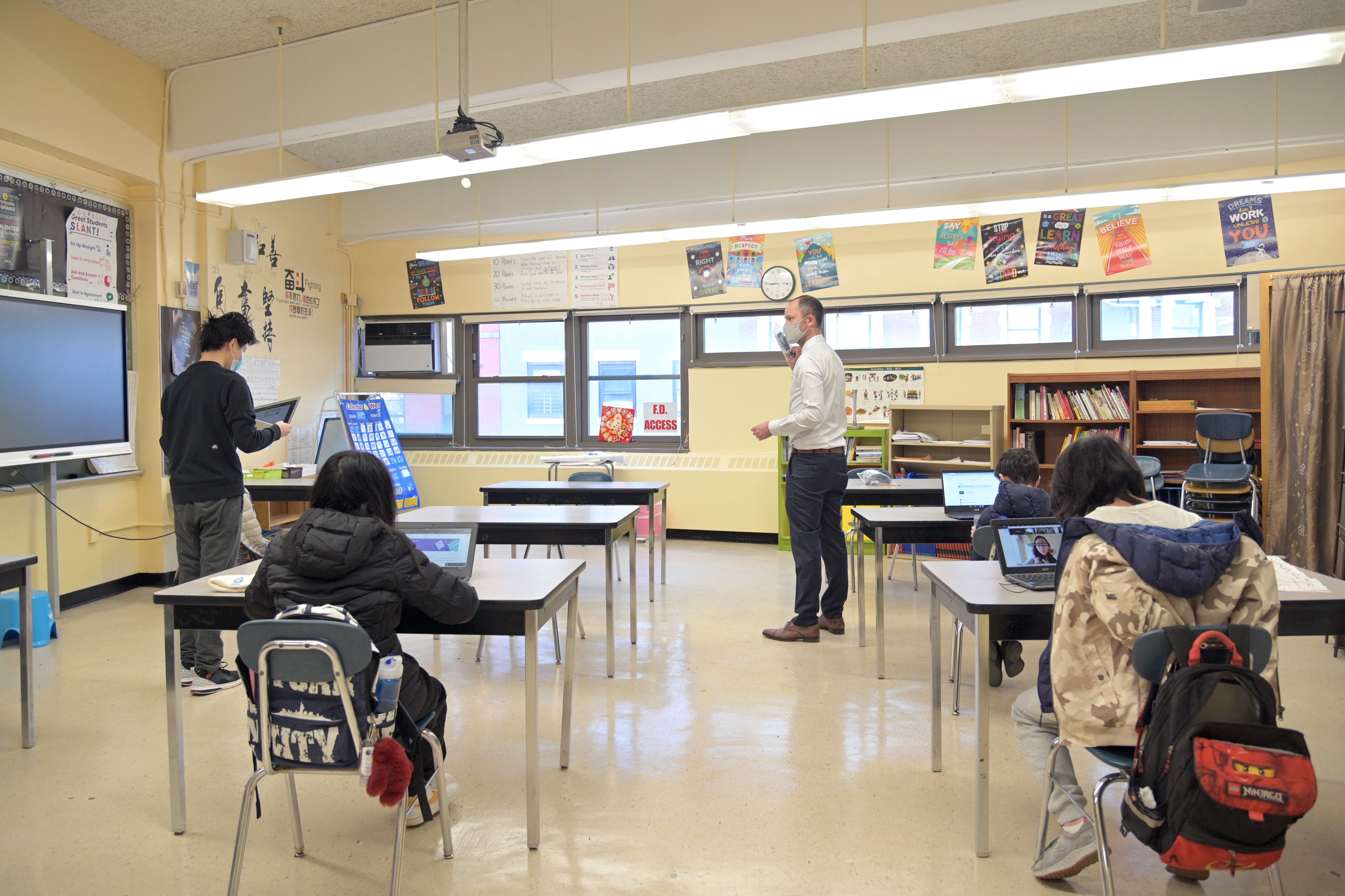 Representative image: A principal helps students settle into a classroom at Sun Yat Sen MS 131 on 25 February 2021 in New York City