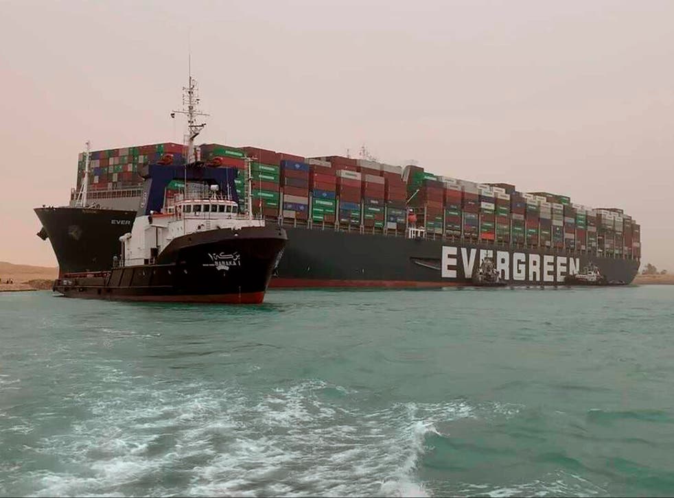 A boat navigates in front of the Ever Given, a gigantic container ship that ran aground in the Suez Canal