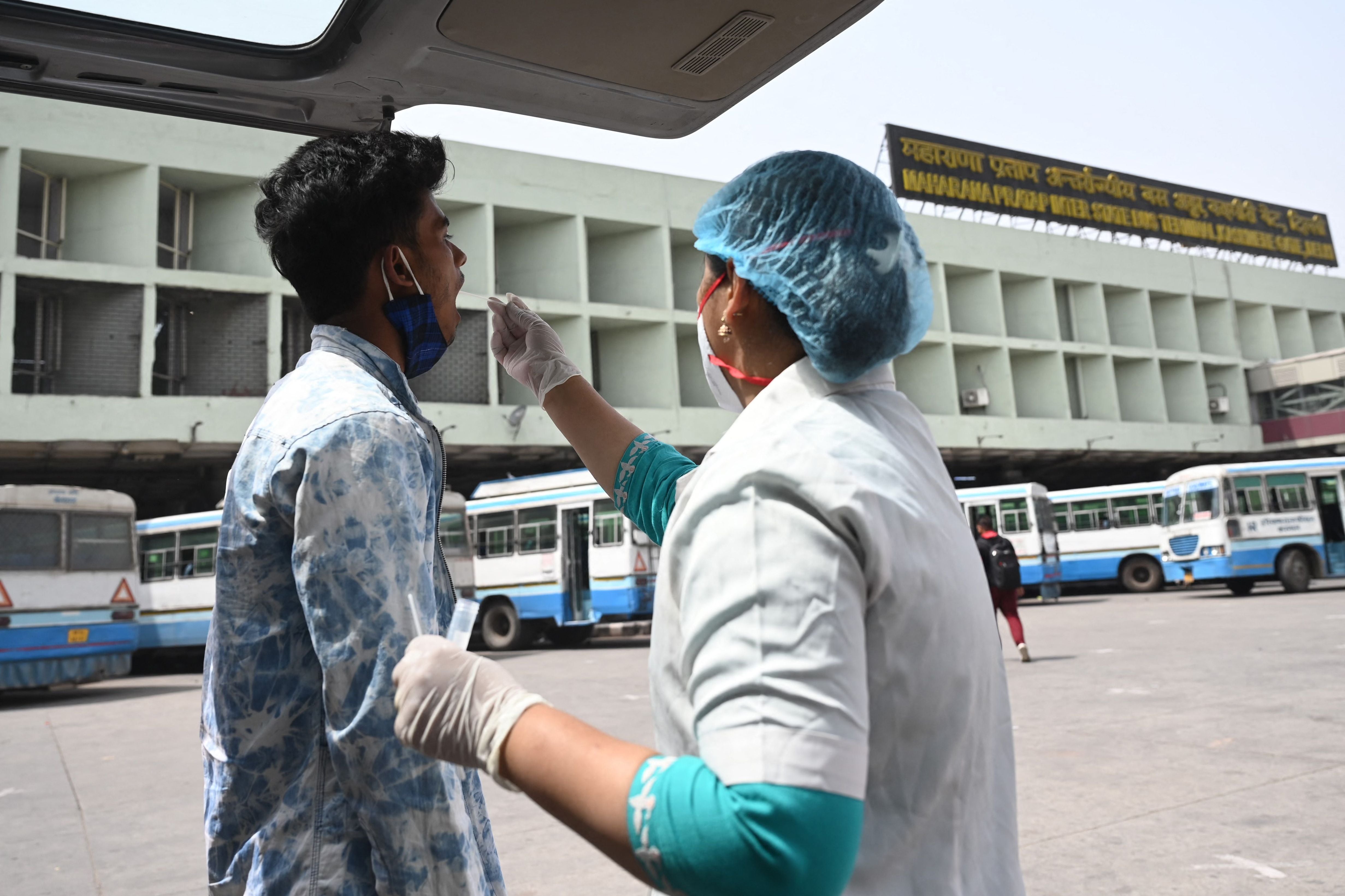 A health worker collects a swab sample for Covid-19 test at the main central bus terminal in Delhi on 24 March