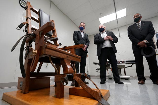Virginia Governor Ralph Northam, left, looks over the electric chair in the death chamber at Greensville Correctional Centre before signing legislation outlawing the death penalty in the state