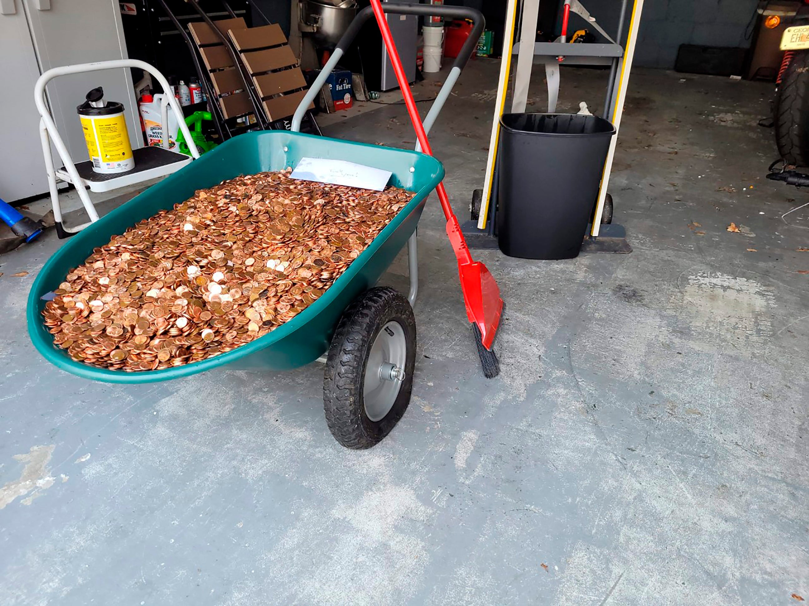 Andreas Flaten moved the more than 90,000 oil-covered pennies from his driveway to a wheelbarrow, causing its tires to deflate