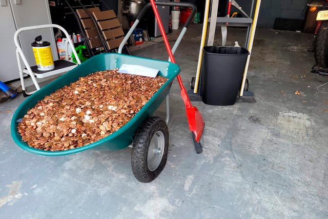 <p>Andreas Flaten moved the more than 90,000 oil-covered pennies from his driveway to a wheelbarrow, causing its tires to deflate </p>