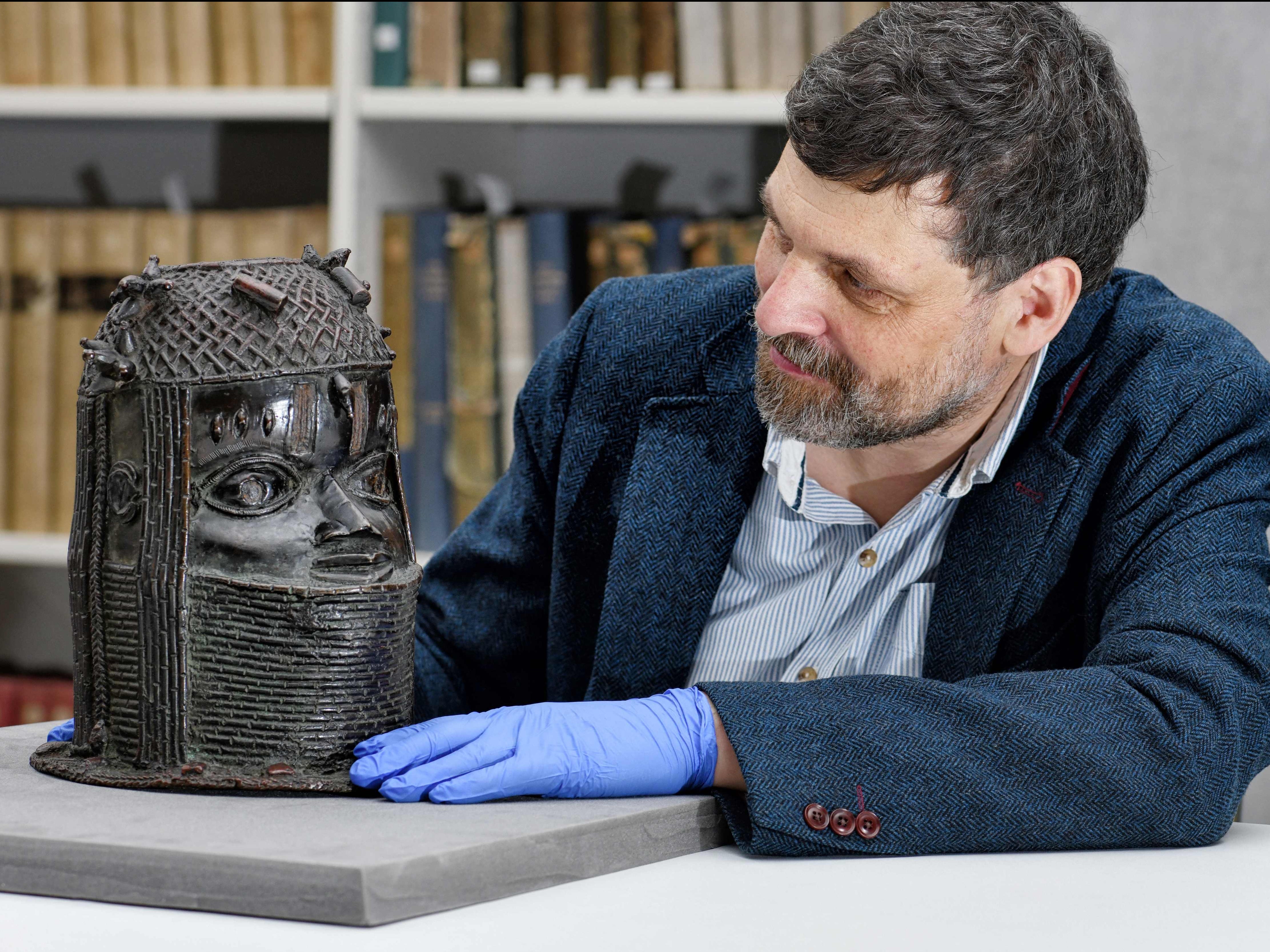 Neil Curtis, Head of Museums and Special Collections posing by a bronze sculpture depicting an "Oba" (king) of Benin acquired by the University at auction in 1957
