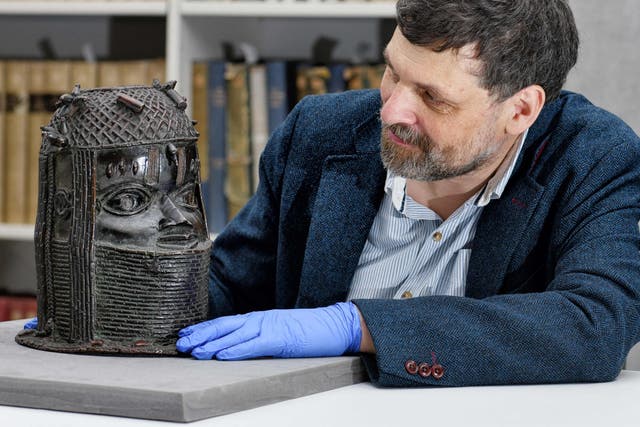 Neil Curtis, Head of Museums and Special Collections posing by a bronze sculpture depicting an "Oba" (king) of Benin acquired by the University at auction in 1957