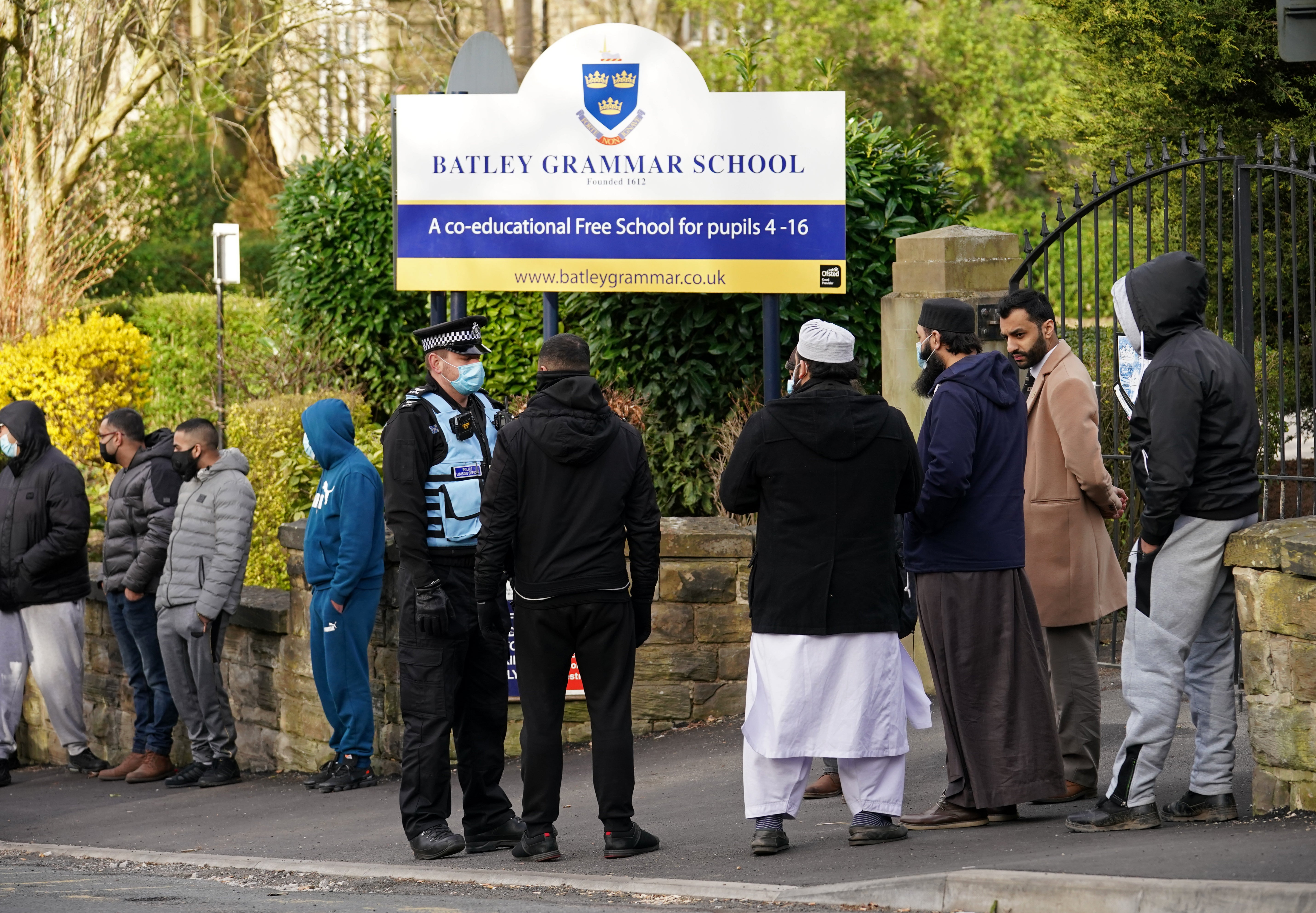 A police officer stands with protesters outside Batley Grammar School