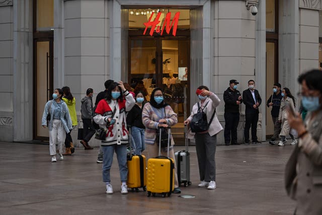 <p>People walk past a store of Swedish clothing giant H&M in Shanghai on 26 March 2021</p>