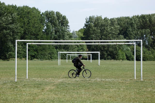 A man wearing a face mask cycles across Hackney Marshes