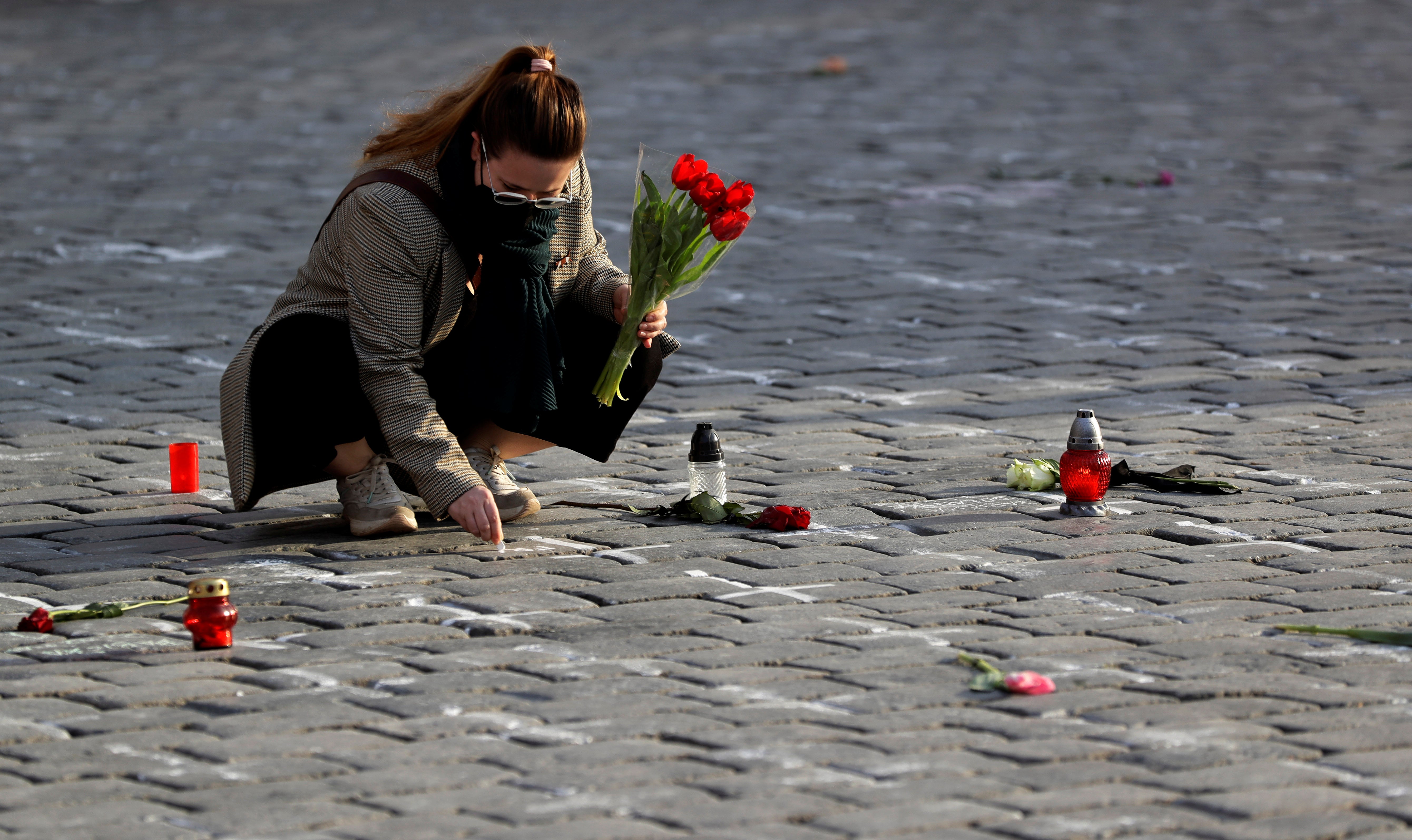 A woman writes a name of her deceased loved one at the Old Town Square