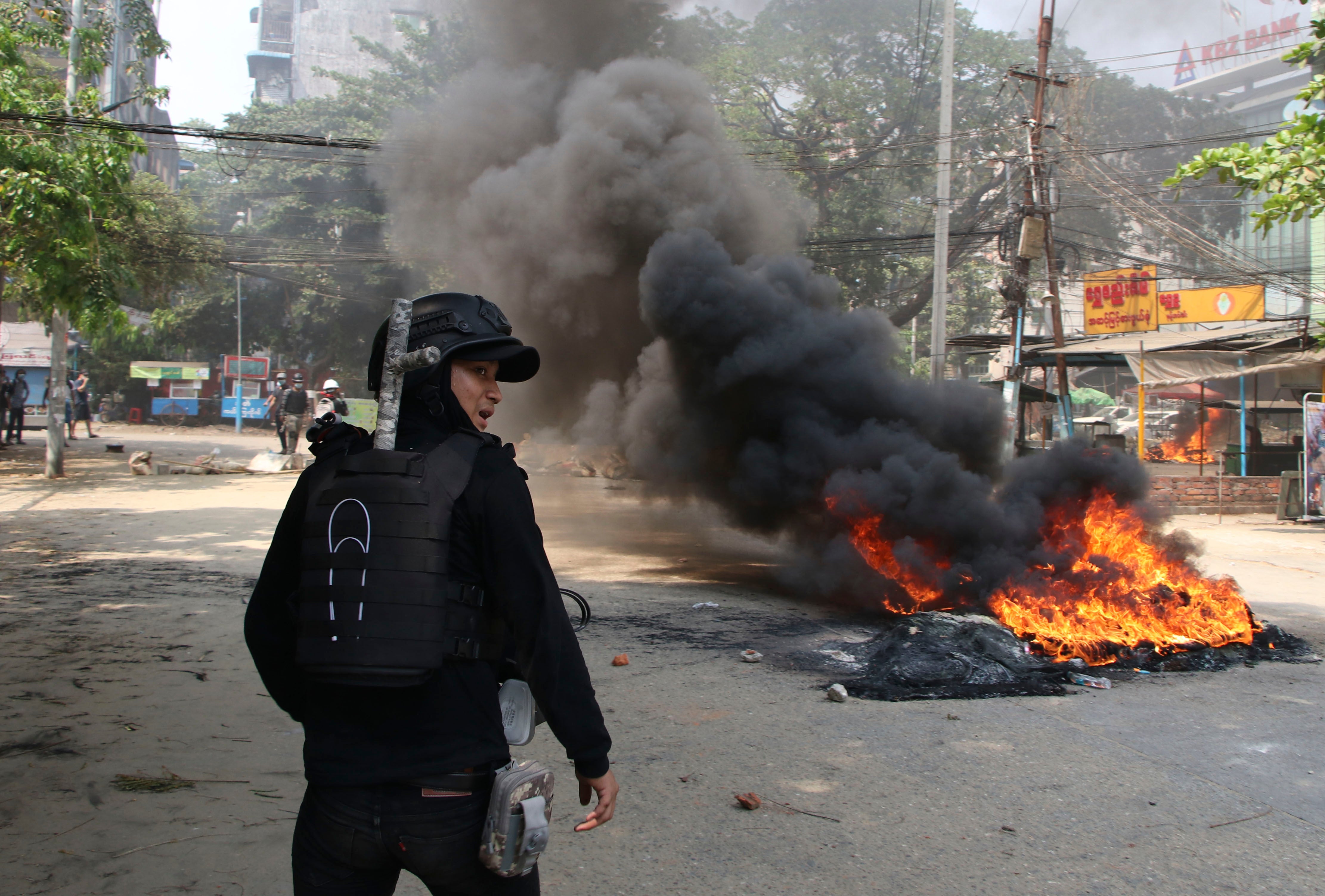 An anti-coup protester stands near a fire during a demonstration in Yangon, Myanmar, on 27 March
