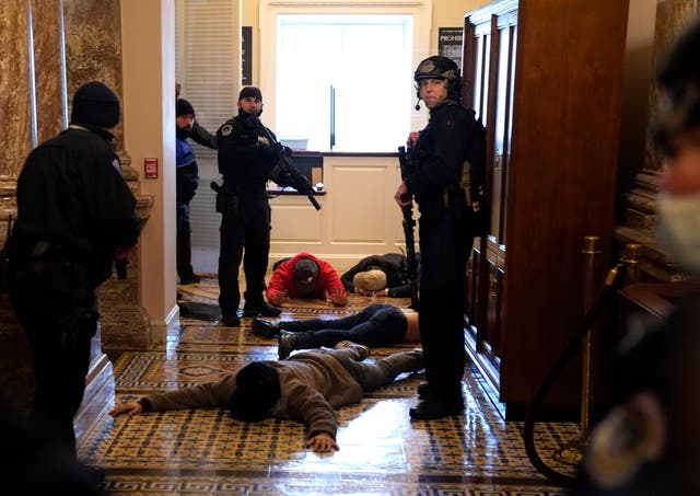 <p>US Capitol police detain protesters outside of the House Chamber during a joint session of Congress on 6 January</p>