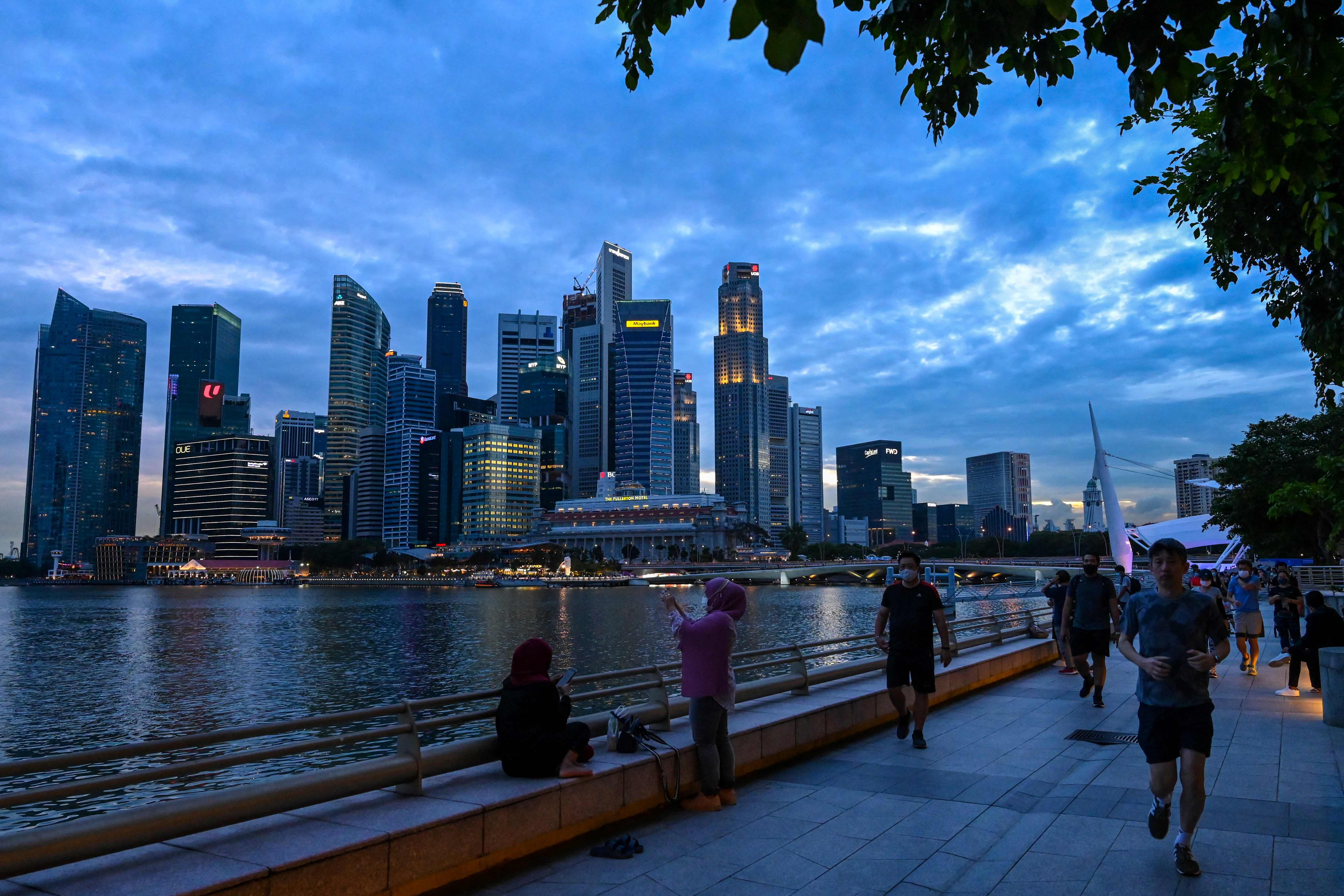 A representational image showing people sitting and walking at the Marina Bay at dusk in Singapore