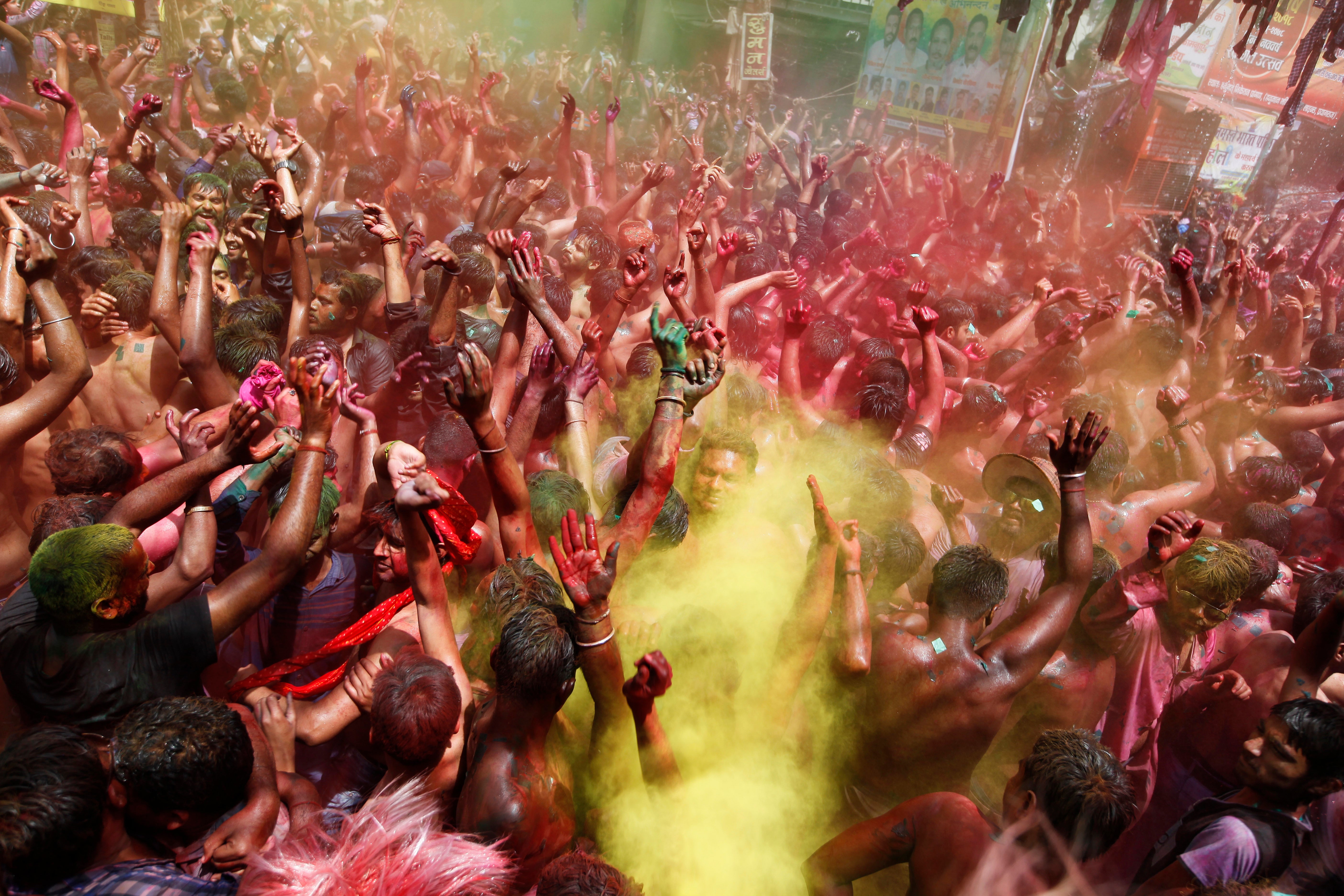 Indian revelers, faces smeared with colored powder, dance during celebrations to mark Holi, the Hindu festival of colors in Prayagraj, India, despite a surge in the virus