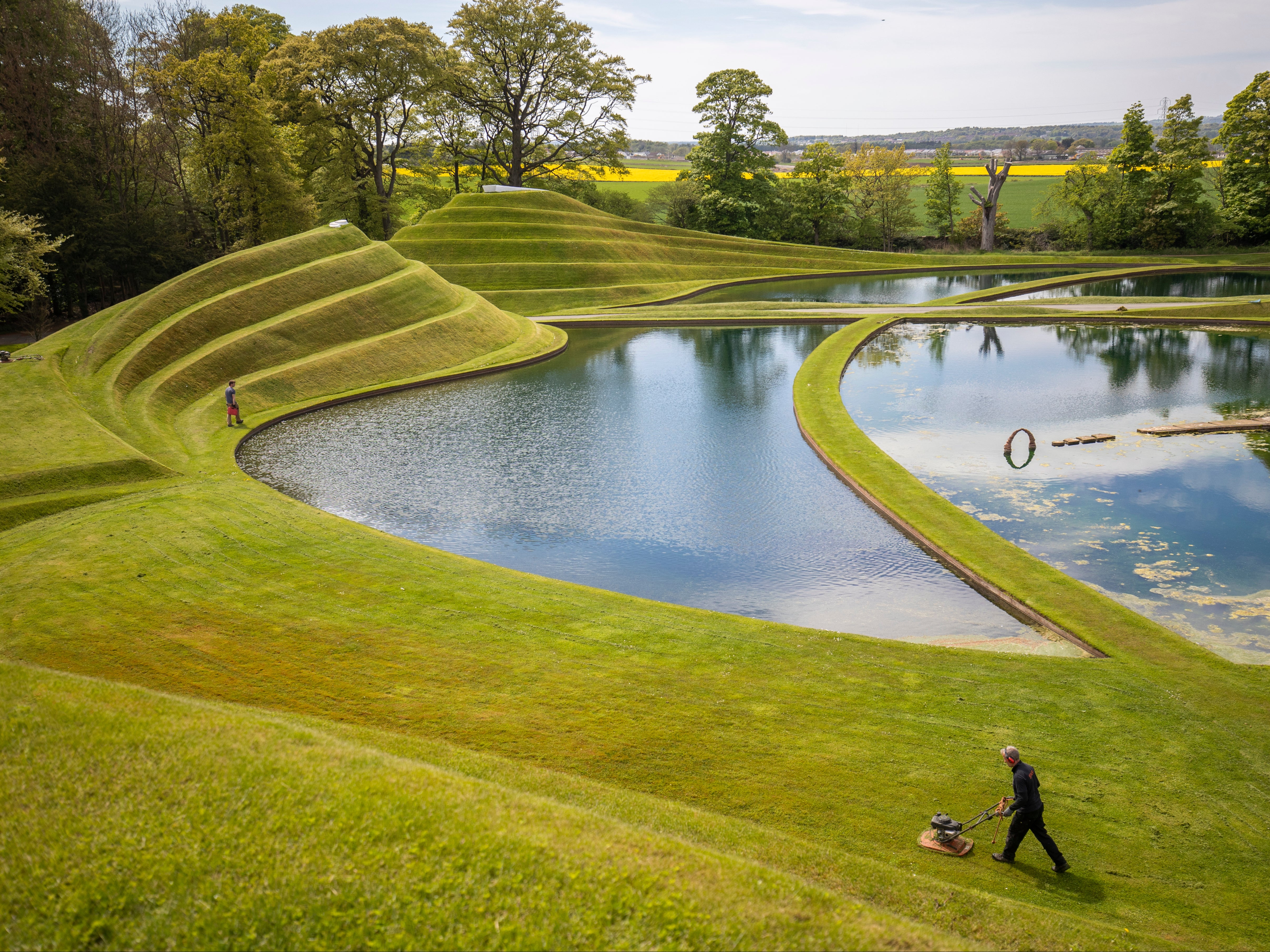 Gardeners mow the grass on the Cells of Life landforms, created by landscape architect Charles Jeneks, which is one of the site-specific sculptures in the grounds of Jupiter Artland