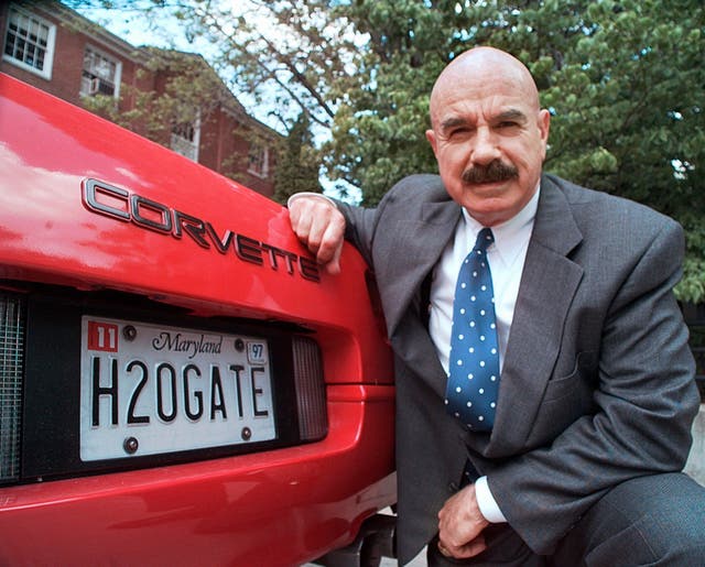 <p>In this 9 June 1997 file photo, G Gordon Liddy kneels next to his Corvette outside the Fairfax, radio station where he broadcasts his syndicated radio talk show</p>