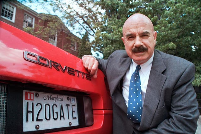 <p>In this 9 June 1997 file photo, G Gordon Liddy kneels next to his Corvette outside the Fairfax, radio station where he broadcasts his syndicated radio talk show</p>