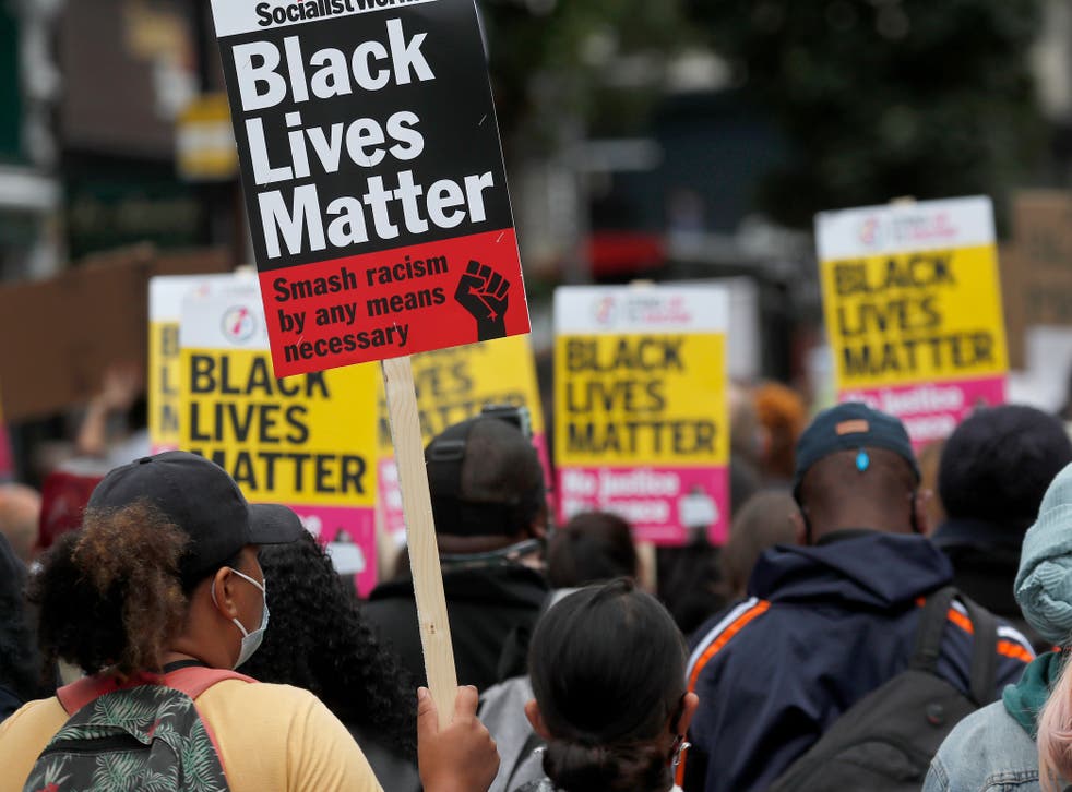 <p>Black Lives Matter protesters hold posters as they march through London’s Notting Hill in August 2020</p>