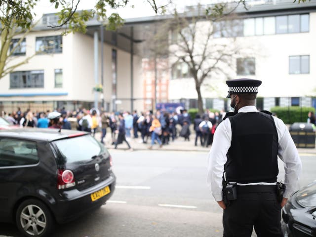 A police officer outside Pimlico Academy School, west London, where students have staged a walkout in protest over a school uniform policy that they claim is discriminatory and racist