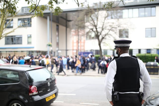 A police officer outside Pimlico Academy School, west London, where students have staged a walkout in protest over a school uniform policy that they claim is discriminatory and racist