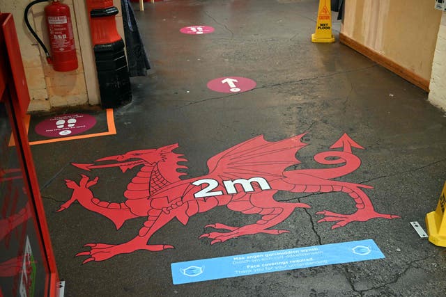 Signage encouraging social distancing as a measure to combat infections of the novel coronavirus are seen on the floor at the entrance of the market in Wrexham, North Wales