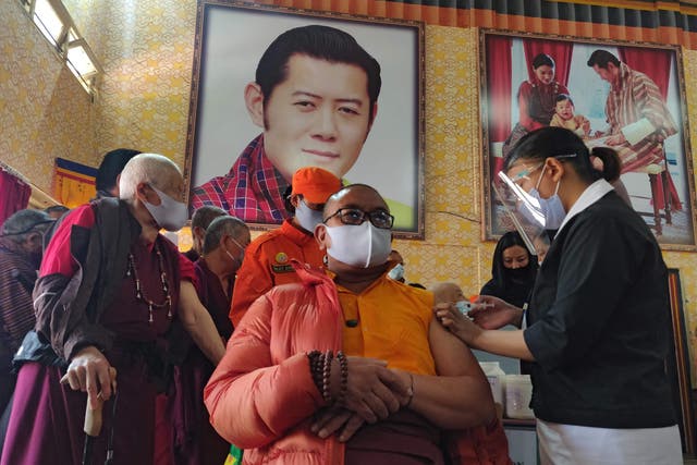 <p>A health worker inoculates a Buddhist monk on the first day of vaccination in Bhutan.</p>