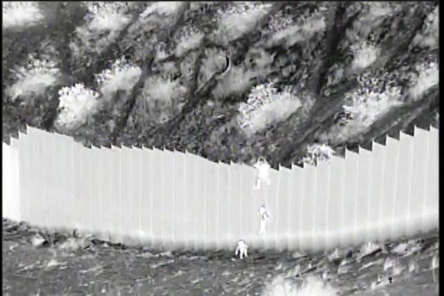 <p>This Tuesday, March 30, 2021 photo taken from night video provided by the U.S. Customs and Border Protection shows a smuggler dropping children from the top of border barrier in Santa Teresa, N.M.</p>