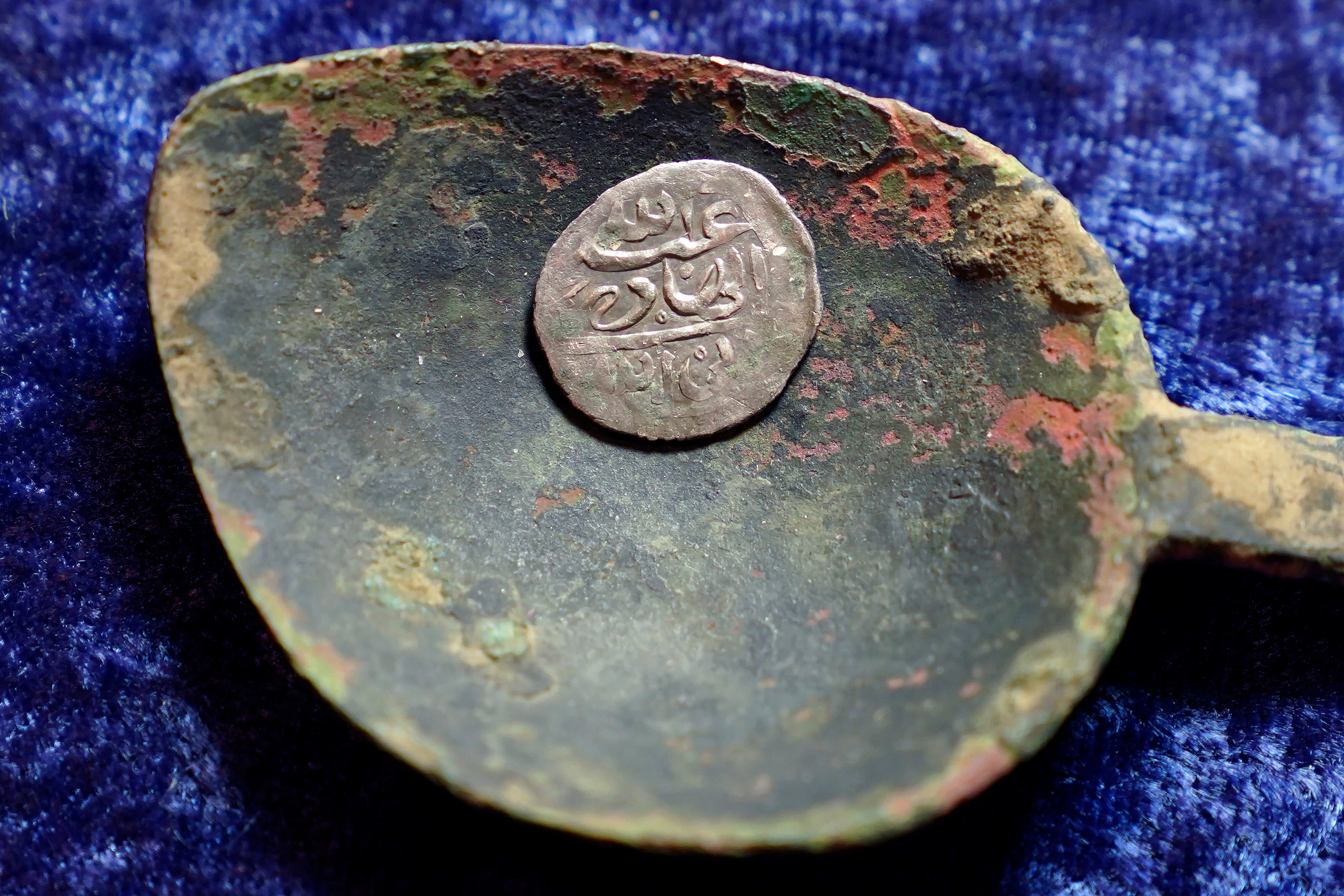A 17th century Arabian silver coin that research shows was struck in 1693 in Yemen, rests in a 17th century brass spoon on a table, in Warwick, R.I., Thursday, March 11, 2021.