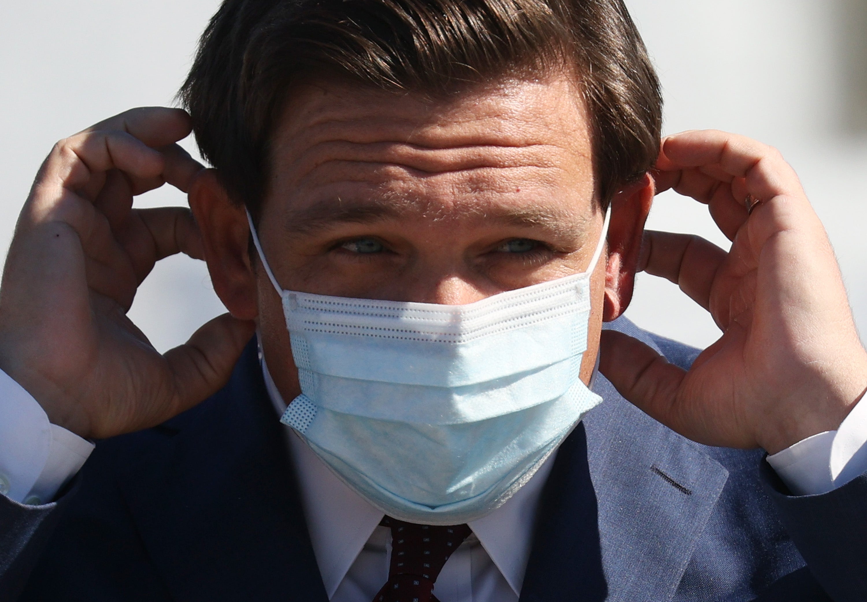 Florida Governor Ron DeSantis places his mask back on after speaking during a press conference about the opening of a Covid-19 vaccination site at the Hard Rock Stadium on 6 January, 2021 in Miami Gardens, Florida. Mr DeSantis has declared a state of emergency for an area at risk of a wastewater flood.