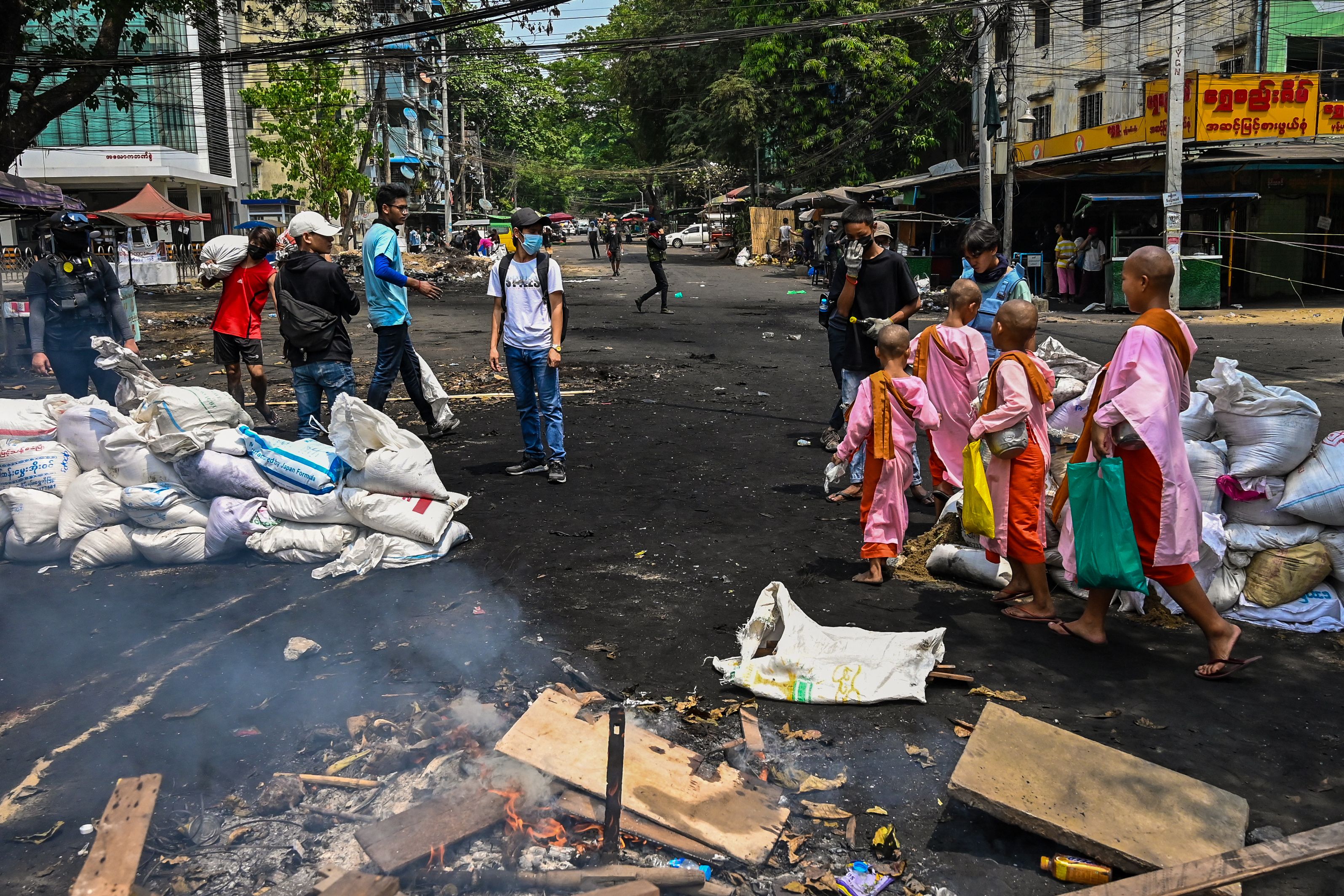 Buddhist nuns in Yangon walk past makeshift barricades erected by protesters demonstrating against the military coup