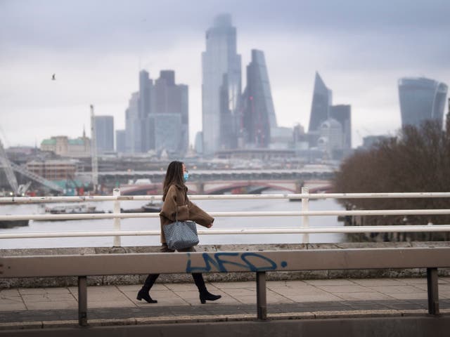 A lone woman wearing a facemask walks over an empty Waterloo Bridge in central London during England's third national lockdown