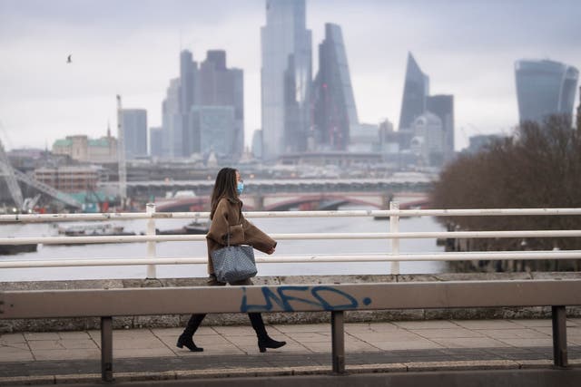 A lone woman wearing a facemask walks over an empty Waterloo Bridge in central London during England's third national lockdown