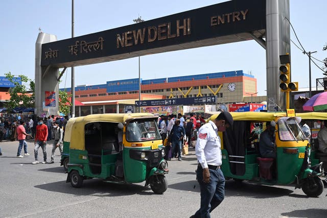<p>A traffic policeman, people and vehicles make their way near an entrance of the New Delhi Railway</p>