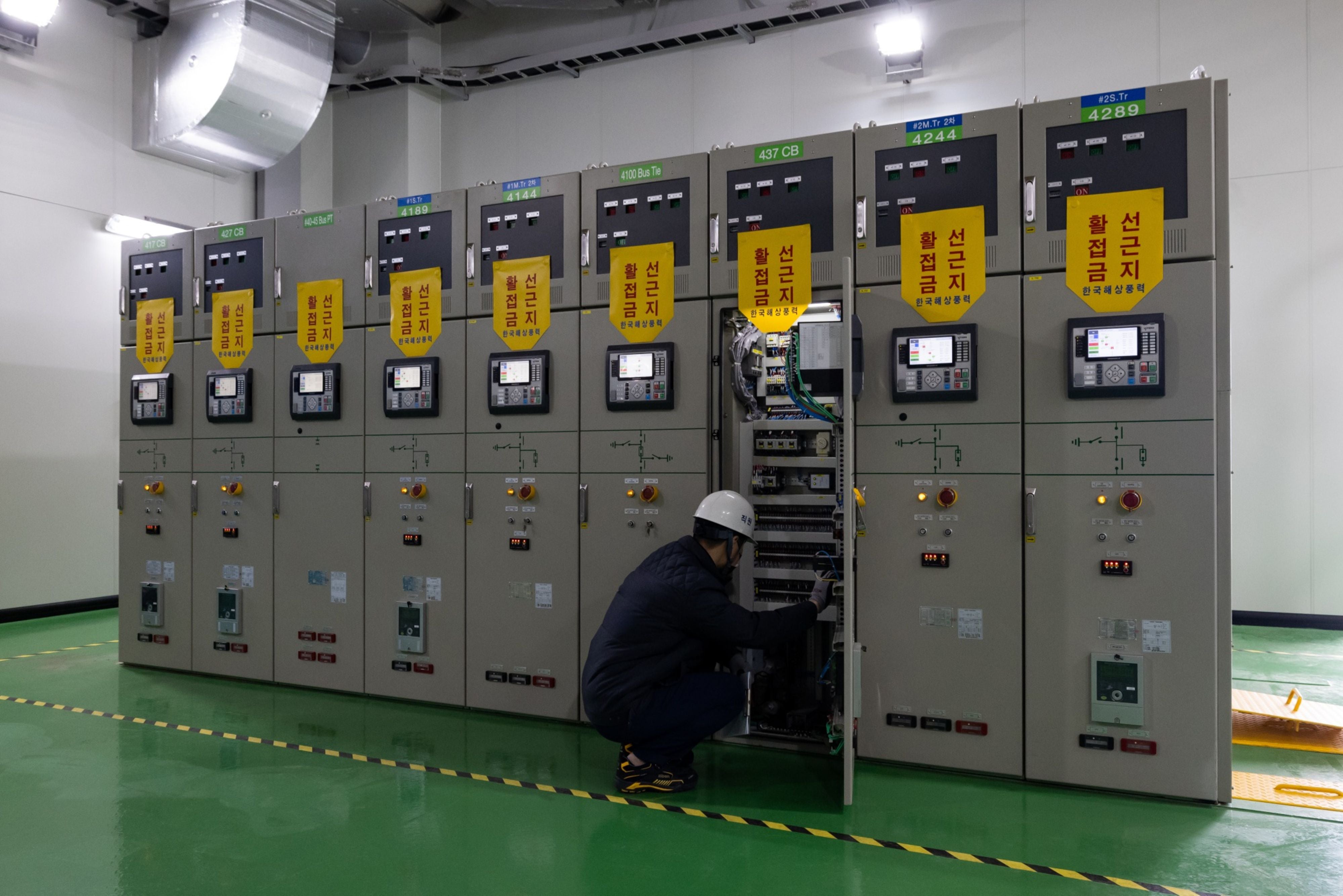 Workers inspect switchgear at the wind farm’s substation