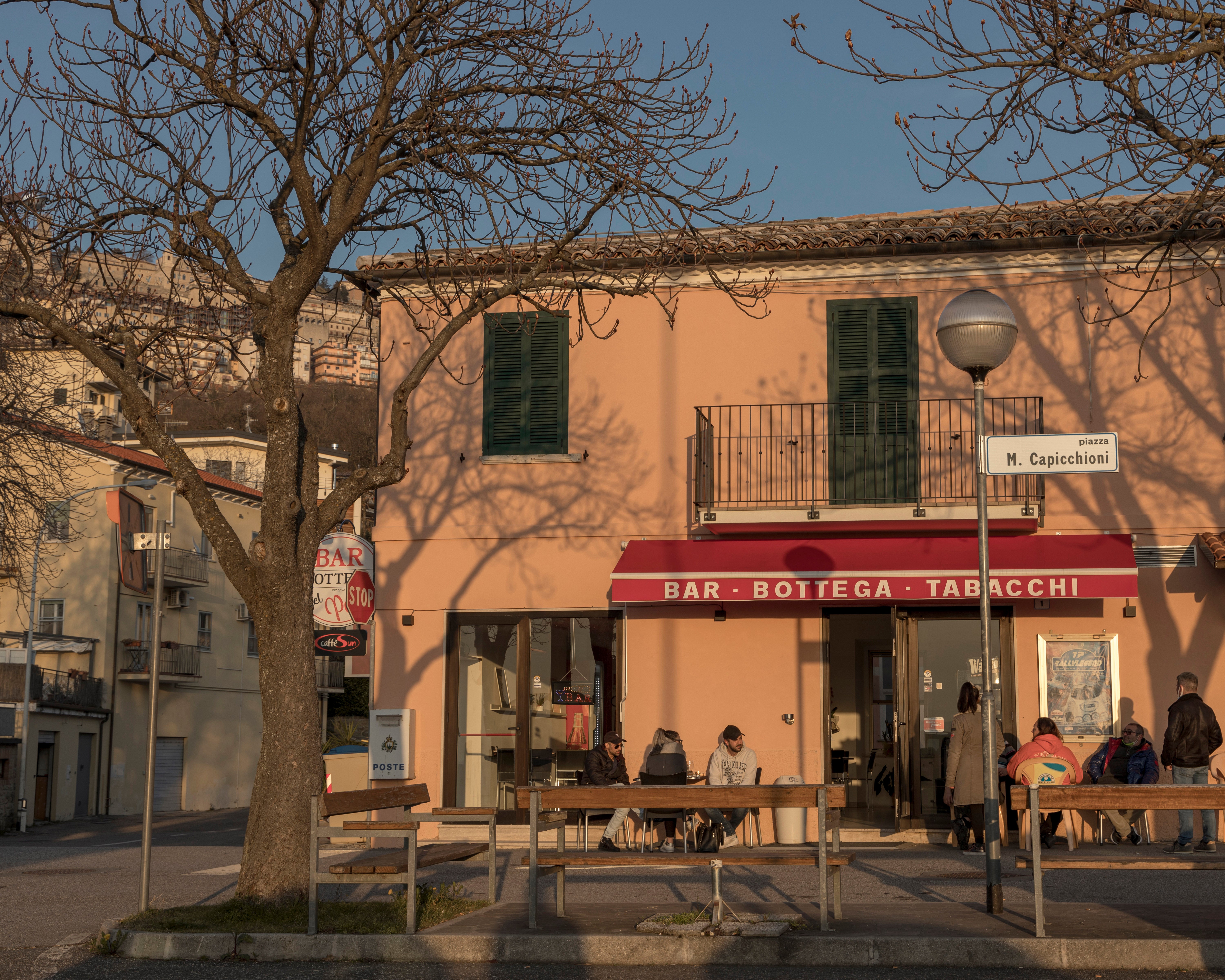 People sit outside a bar in San Marino while Italy has extended its lockdown through April