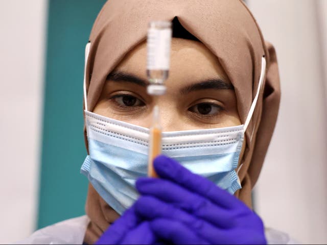 A medical worker prepares an injection with a dose of AstraZeneca coronavirus vaccine at a vaccination centre in Baitul Futuh Mosque in London