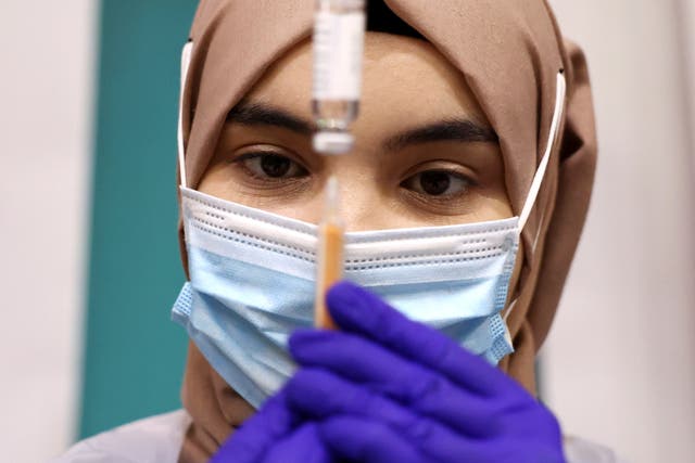 A medical worker prepares an injection with a dose of AstraZeneca coronavirus vaccine at a vaccination centre in Baitul Futuh Mosque in London