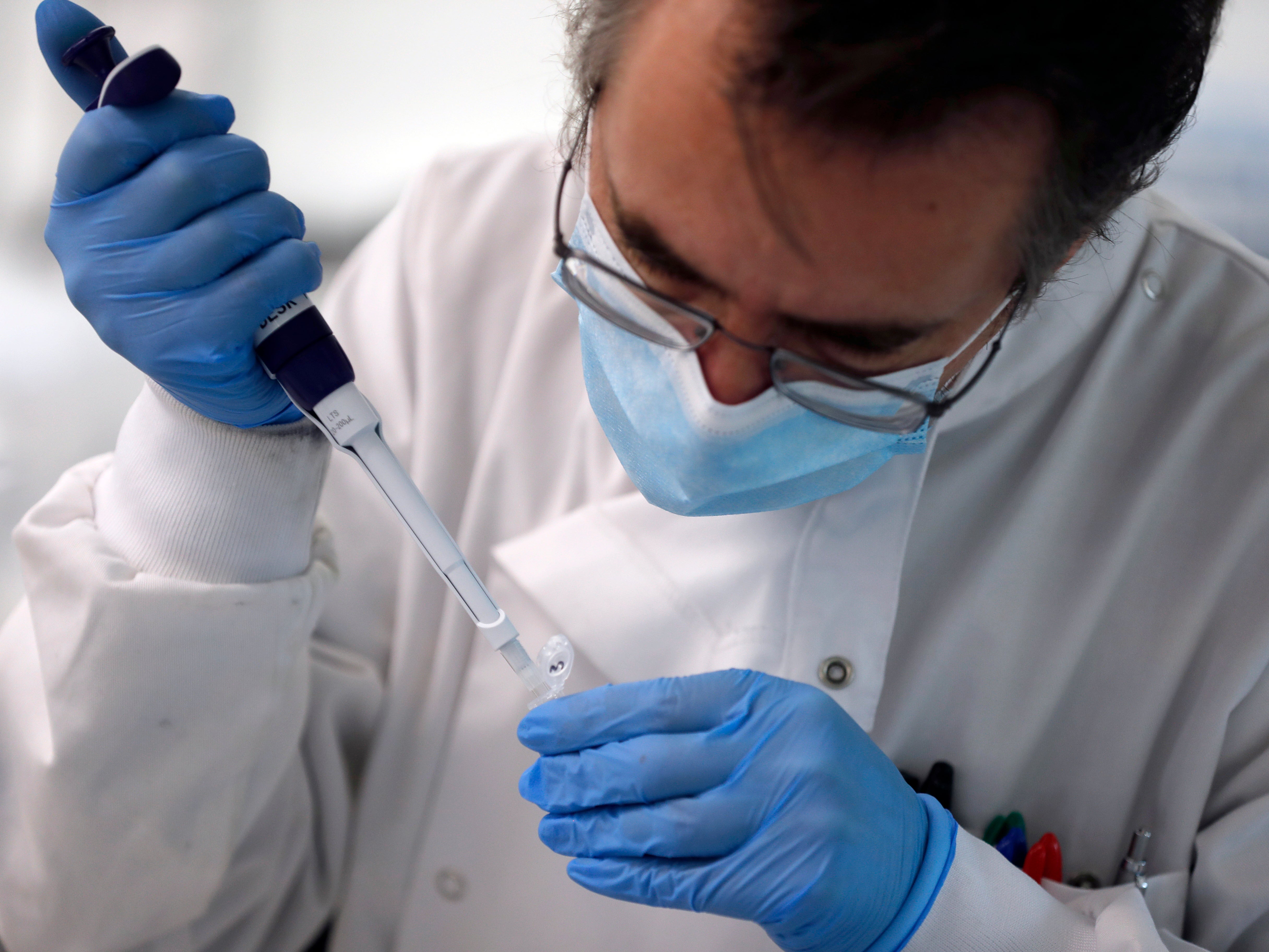 A lab assistant uses a pipette to prepare Coronavirus RNA for sequencing at the Wellcome Sanger Institute that is operated by Genome Research in Cambridge