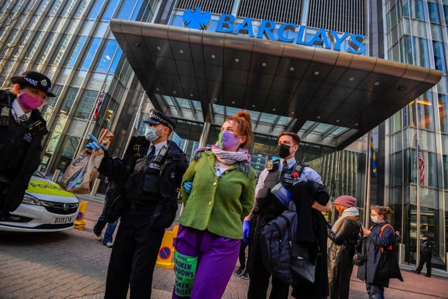 Police officers detain an activist from the Extinction Rebellion outside the Barclays offices in Canary Wharf
