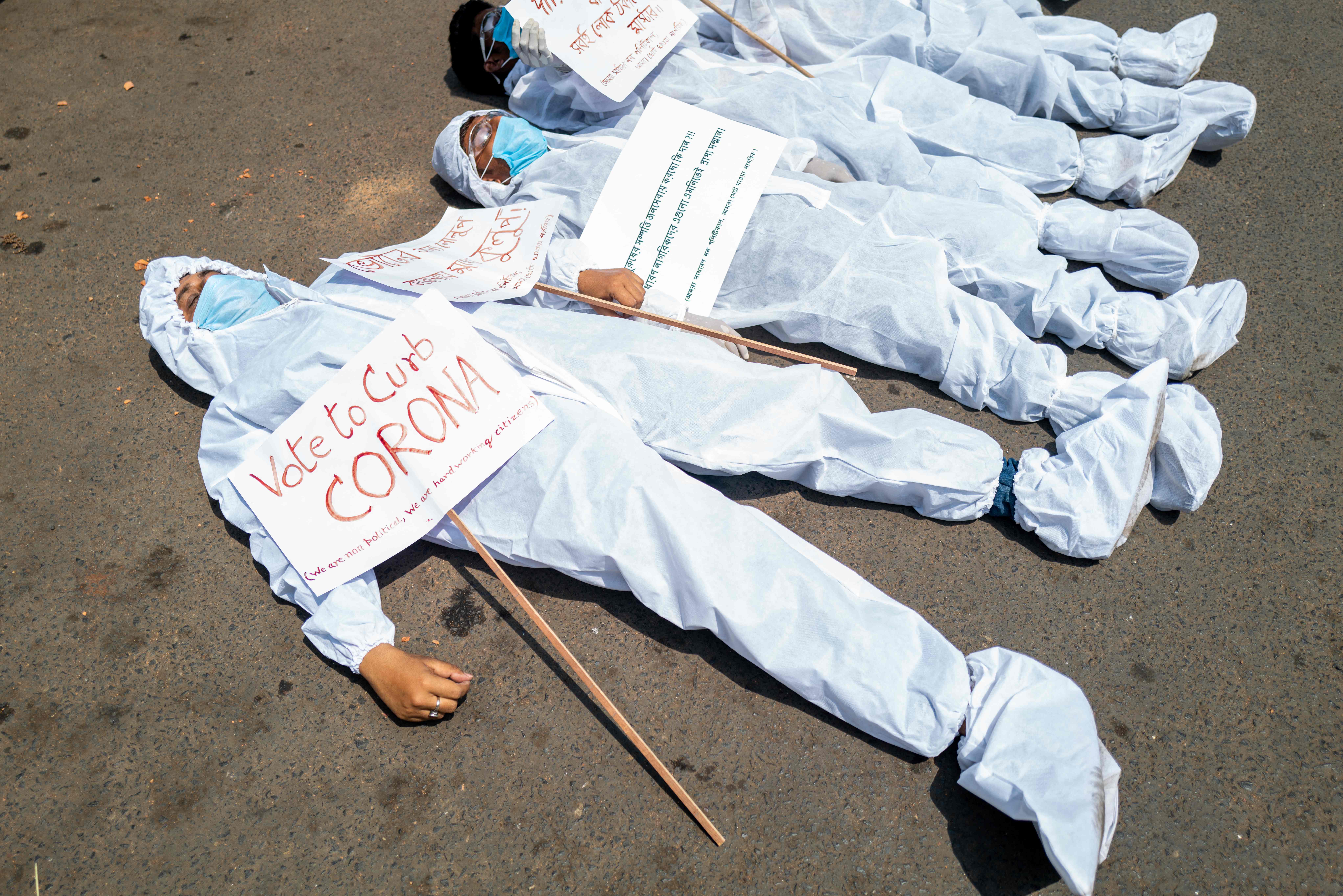 Protesters wearing protective suits and masks display placards laying on the street near the Election Commission office in Kolkata earlier this month
