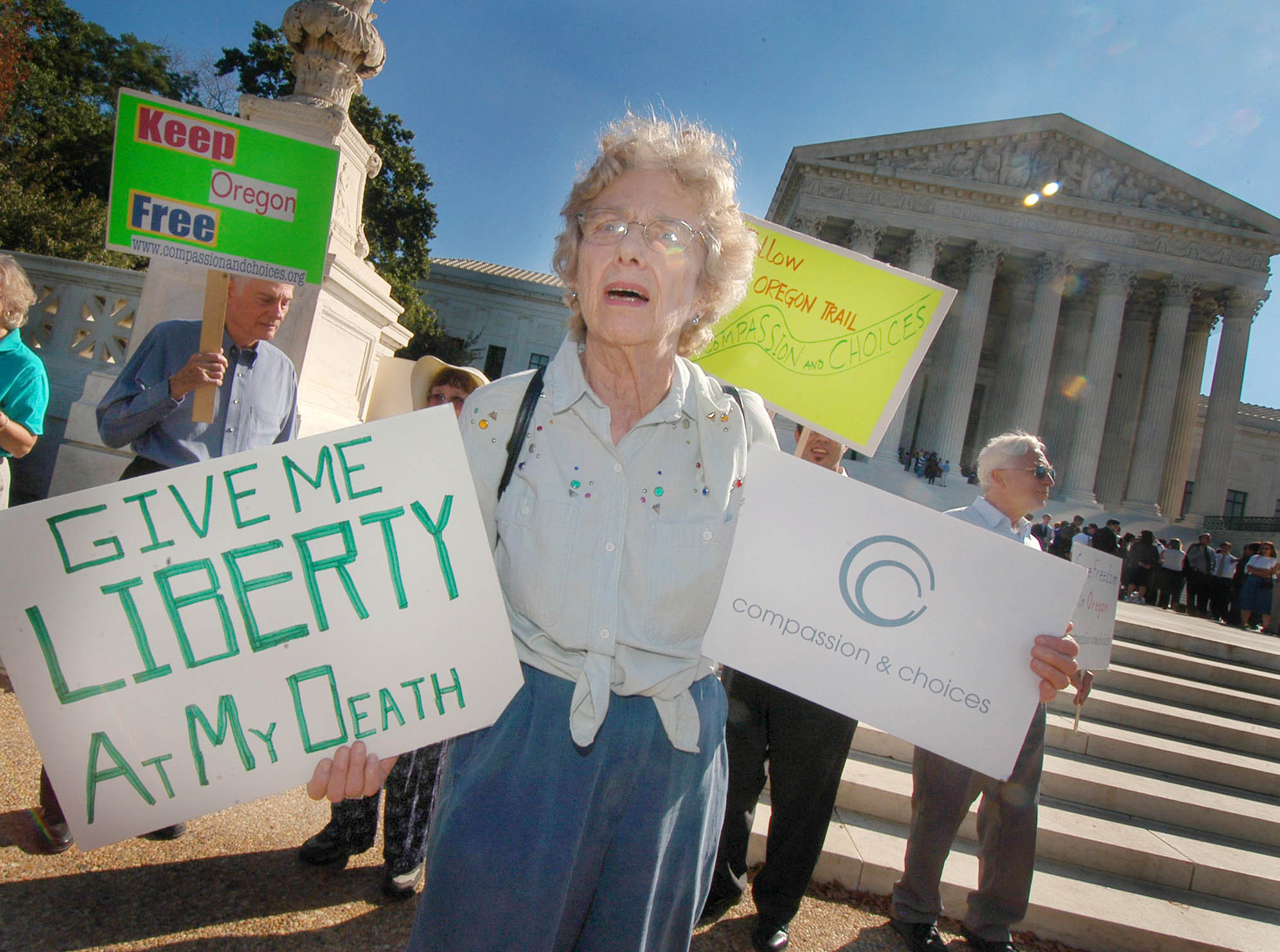 Demonstrators hold signs on the steps of the Supreme Court backing Oregon's assisted suicide law