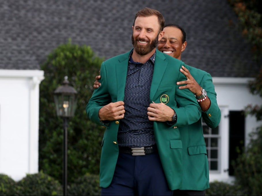 Dustin Johnson receives the Green Jacket from Tiger Woods