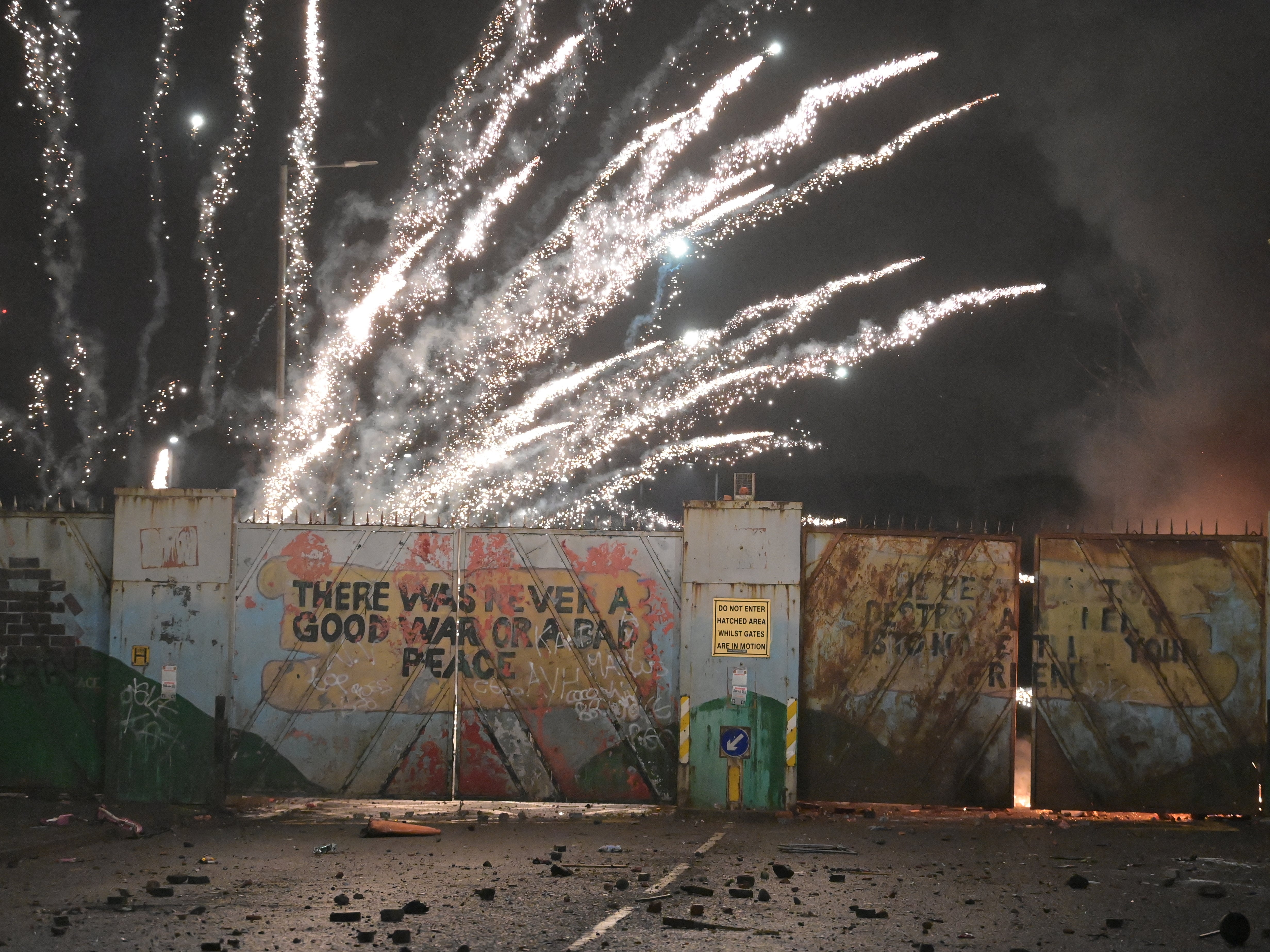 Fireworks explode as youths exchange projectiles through the Peace Gate during clashes at the Springfield Road/Lanark Way interface