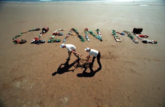 Clean me written on a beach in rubbish (Alamy/PA)