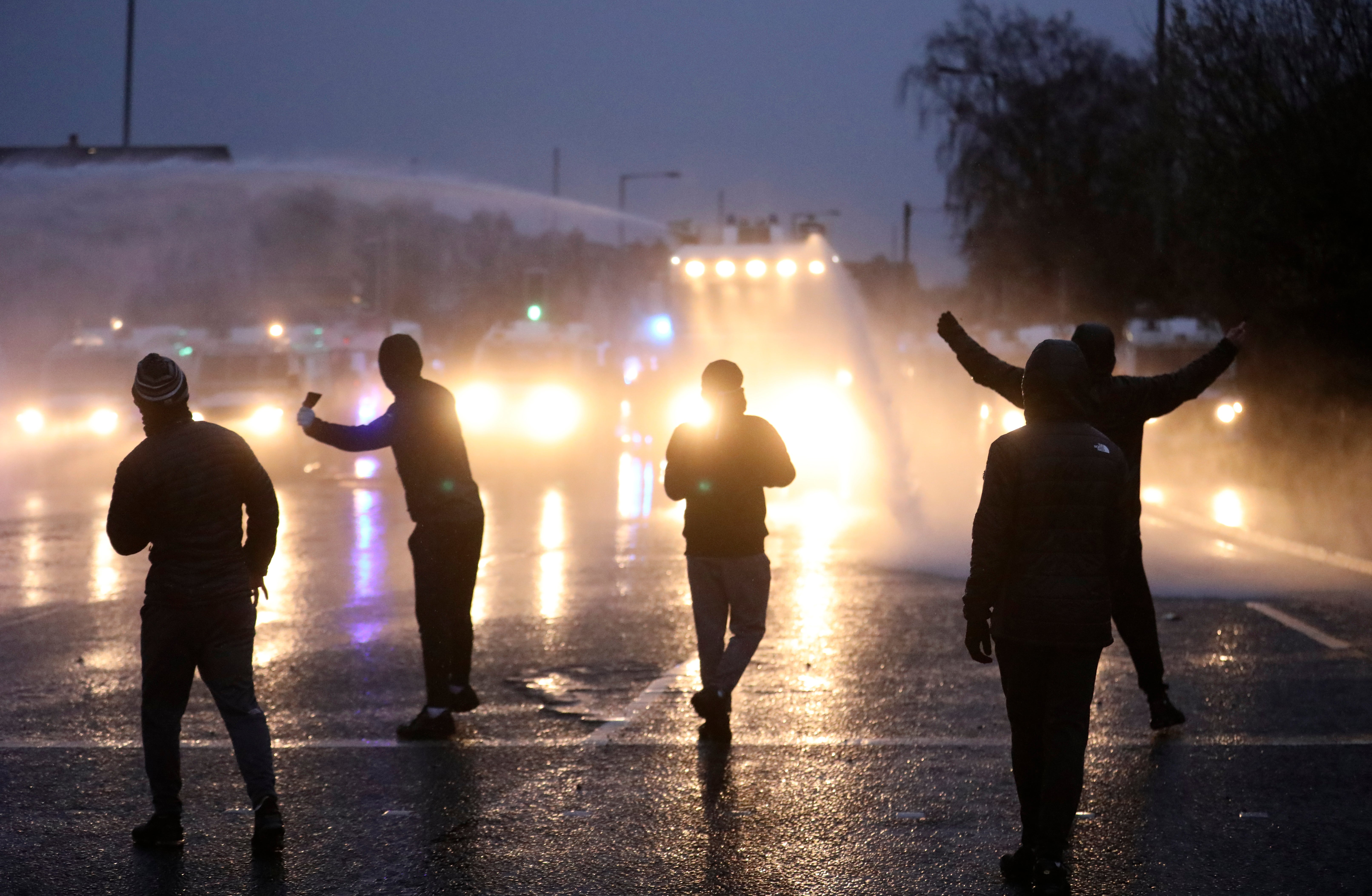 Nationalist youths gesture towards a police line blocking a road near the Peace Wall in Belfast