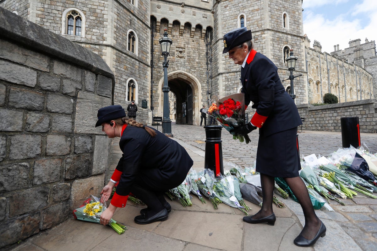 Windsor Castle wardens move flowers which were placed by members of the public