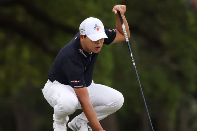 <p>Si Woo Kim lines up a putt with his three-wood</p>