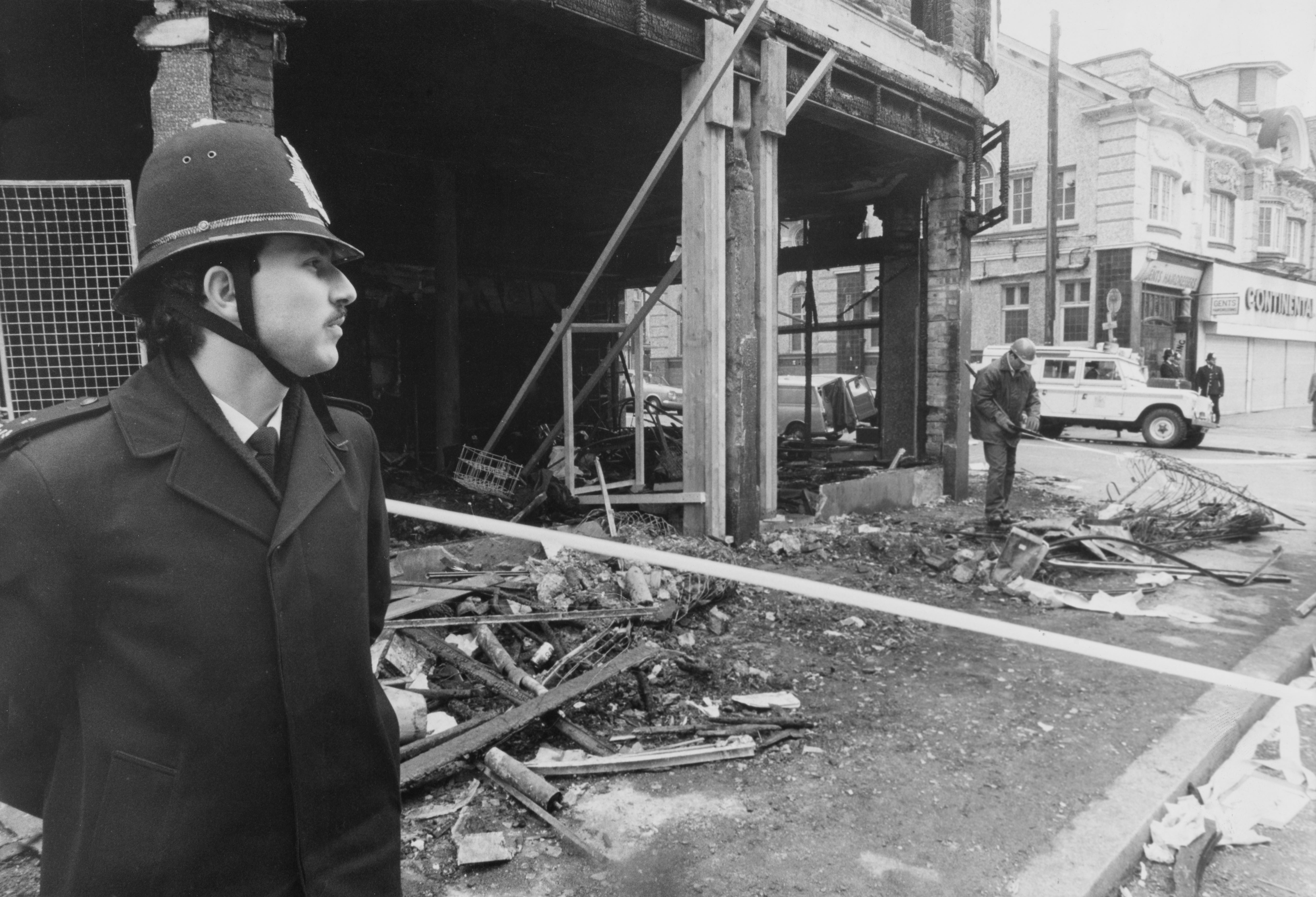 A police officer stands next to a gutted building on Coldharbour Lane after riots erupted on the streets of Brixton in April 1981